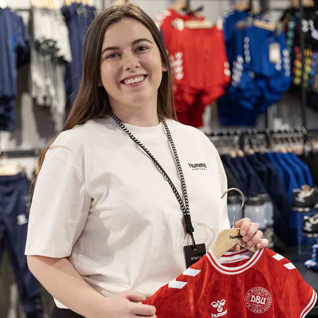 Smiling employee from Hummel in Frederiksberg with a national team jersey.